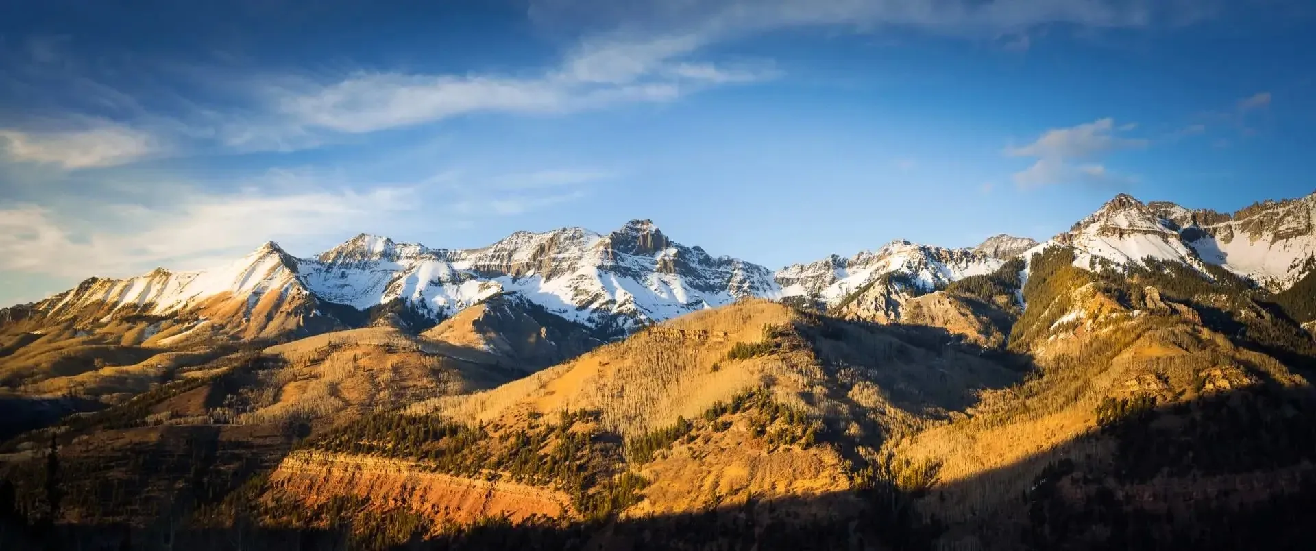 Scenic mountain landscape with snow-capped peaks and rolling hills representing land investment opportunities
